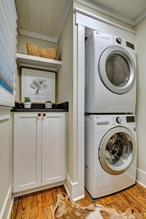 laundry room with cabinets, light hardwood / wood-style flooring, and stacked washer and dryer