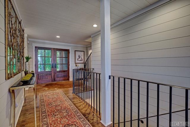 hall featuring wood-type flooring, crown molding, french doors, and wooden walls