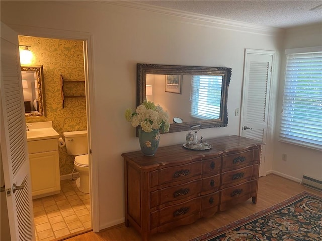 711 Horse Cove Rd Unit C-4, Highlands, NC 28741 - bedroom with ensuite bathroom, wallpapered walls, light wood-type flooring, and a textured ceiling