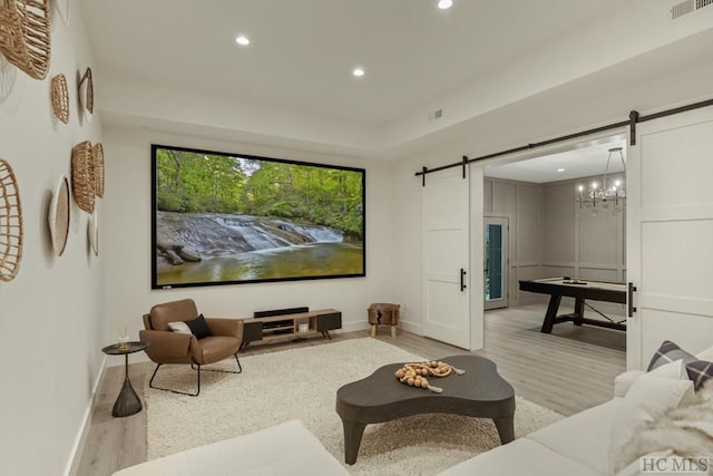 cinema room with a barn door and light hardwood / wood-style floors