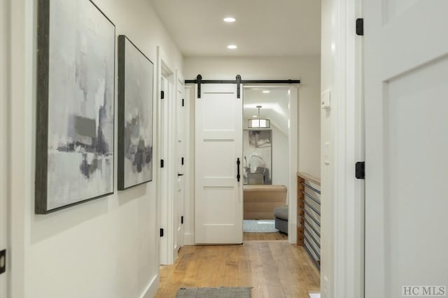 corridor featuring a barn door and light wood-type flooring