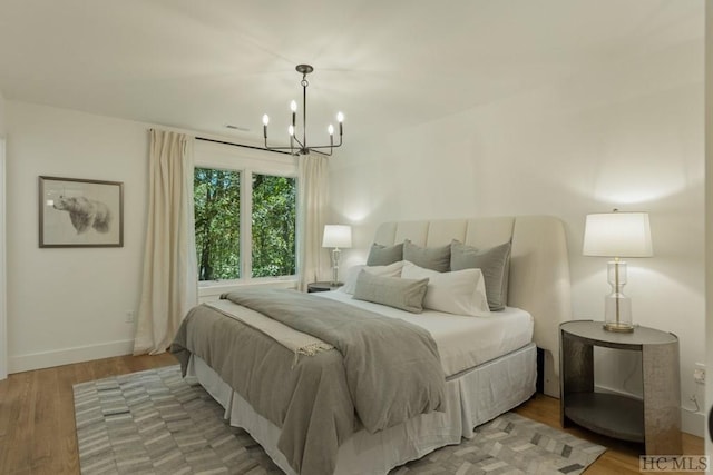 bedroom with an inviting chandelier and light wood-type flooring