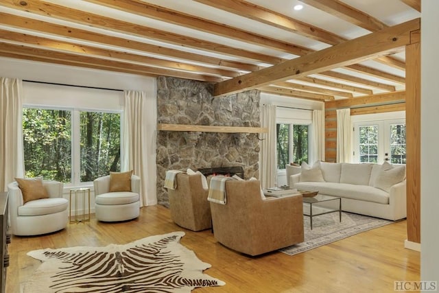 sunroom featuring beamed ceiling, a stone fireplace, and french doors