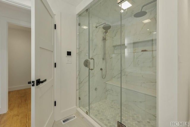 bathroom with hardwood / wood-style flooring and a shower with shower door