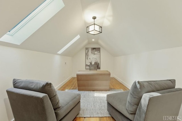 interior space with vaulted ceiling with skylight and light hardwood / wood-style floors