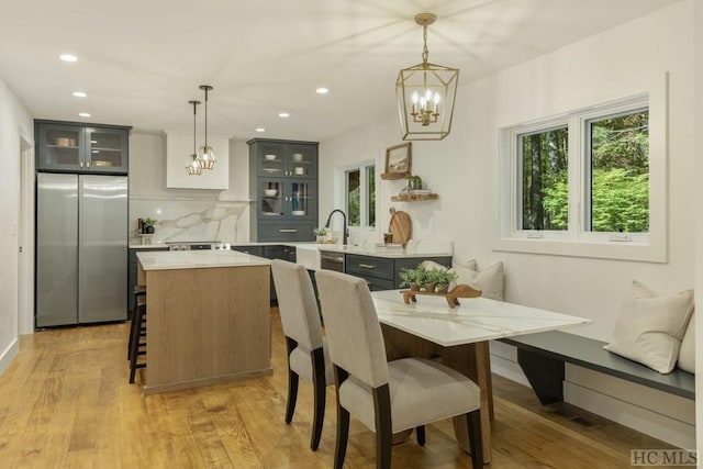 dining area with plenty of natural light, sink, an inviting chandelier, and light hardwood / wood-style floors