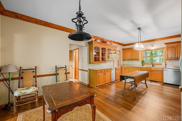 kitchen featuring dishwasher, wood-type flooring, crown molding, and decorative light fixtures