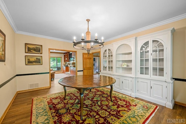 dining area with crown molding, a chandelier, and dark wood-type flooring