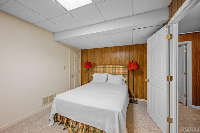 bedroom featuring wooden walls and a drop ceiling