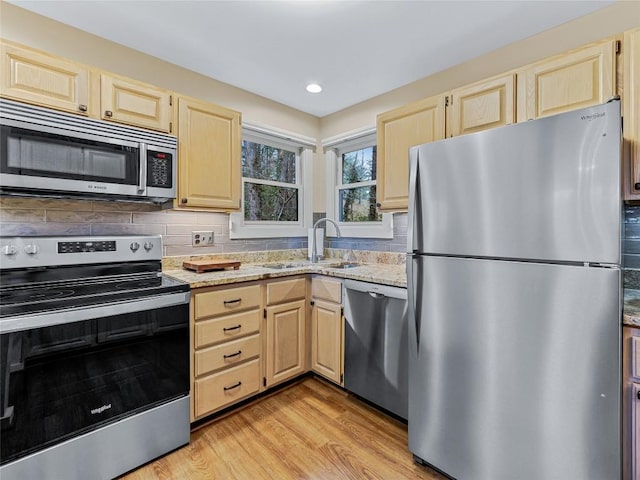 kitchen featuring a sink, light brown cabinets, light stone countertops, and stainless steel appliances