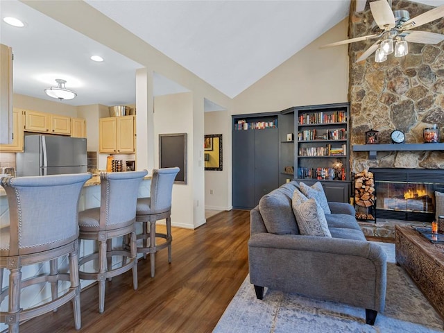 living area with wood finished floors, a ceiling fan, baseboards, recessed lighting, and a stone fireplace