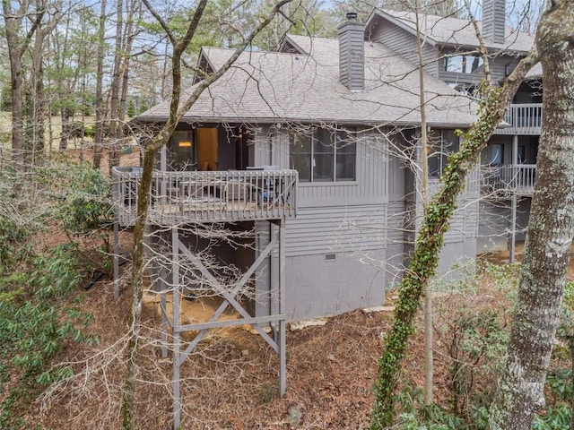 rear view of house featuring crawl space, a chimney, and a shingled roof