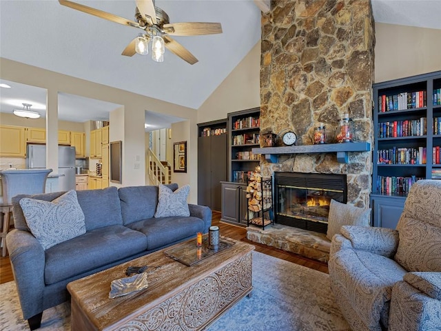 living room with a stone fireplace, stairs, light wood-type flooring, and ceiling fan