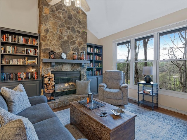 living area with a stone fireplace, high vaulted ceiling, wood finished floors, and a ceiling fan