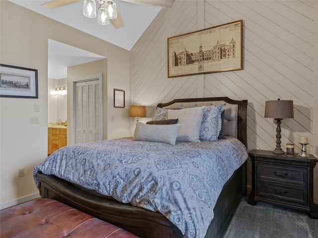 carpeted bedroom featuring lofted ceiling, ceiling fan, a closet, wood walls, and connected bathroom