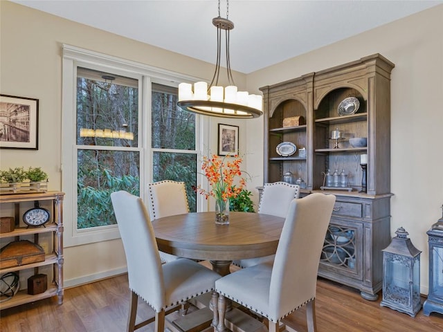 dining space with baseboards, wood finished floors, and a chandelier