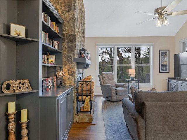 living area with a ceiling fan, vaulted ceiling, and wood finished floors