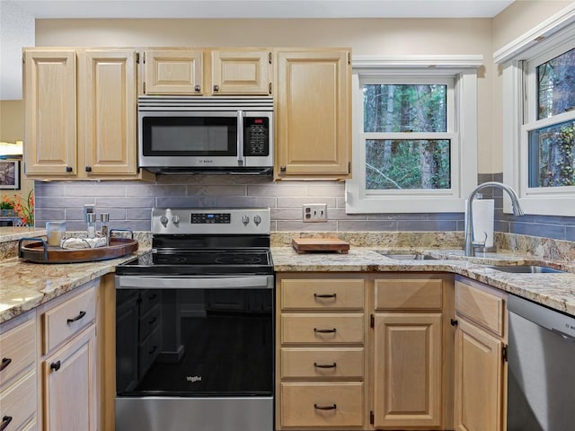 kitchen with a sink, decorative backsplash, appliances with stainless steel finishes, and light brown cabinets