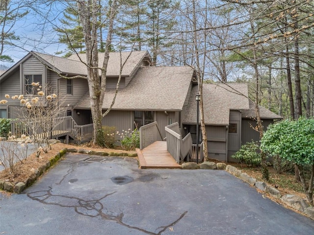 view of front of home with a patio area, roof with shingles, and a wooden deck