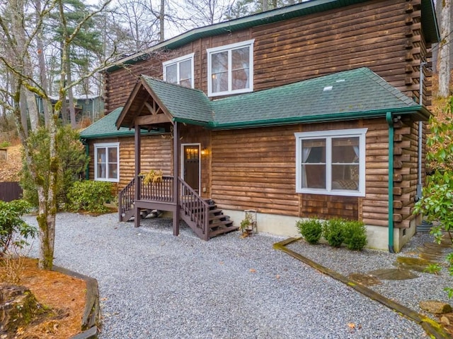 cabin with log siding and a shingled roof