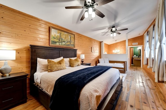 bedroom with light wood finished floors, wood walls, and lofted ceiling