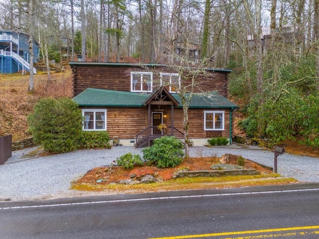 cabin featuring roof with shingles and gravel driveway