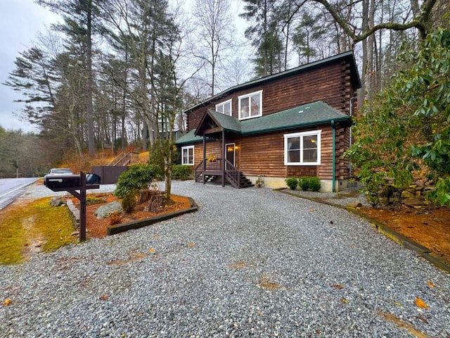 log home with log exterior and gravel driveway