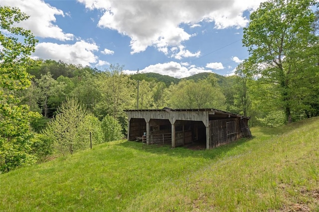 view of outbuilding with a forest view, an outbuilding, and an exterior structure
