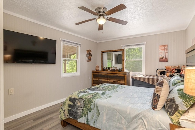 bedroom featuring wood finished floors, ornamental molding, a textured ceiling, baseboards, and ceiling fan
