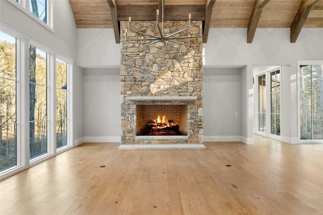 unfurnished living room featuring baseboards, wooden ceiling, wood finished floors, a fireplace, and high vaulted ceiling