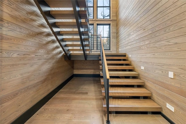 stairway with wood walls and wood finished floors