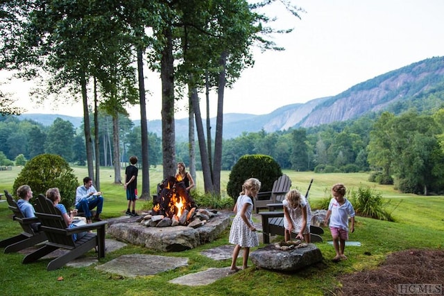 view of community with an outdoor fire pit, a lawn, and a mountain view