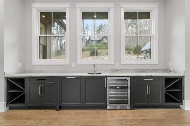 bar with light wood finished floors, wine cooler, and a sink