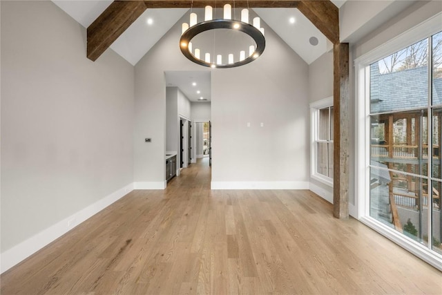 interior space with light wood-style floors, beam ceiling, high vaulted ceiling, and baseboards