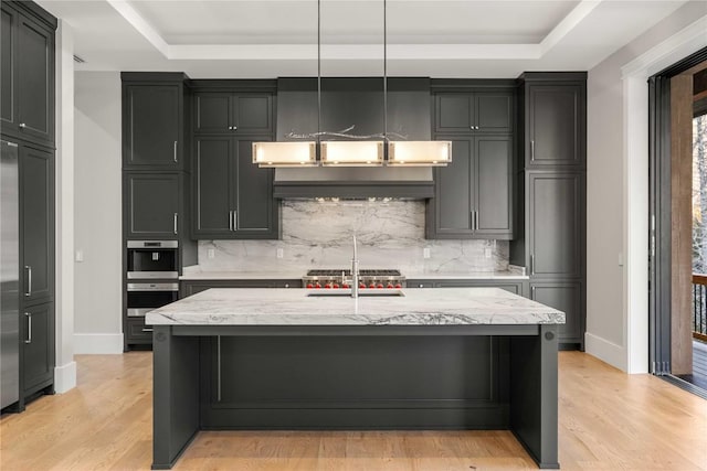 kitchen with light wood finished floors, tasteful backsplash, and a raised ceiling