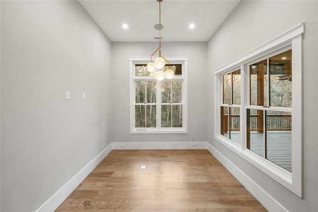 unfurnished dining area featuring a chandelier, recessed lighting, light wood-style flooring, and baseboards