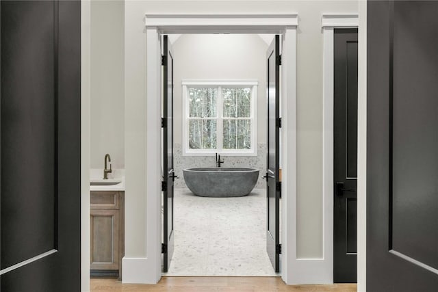 corridor featuring light wood finished floors and a sink