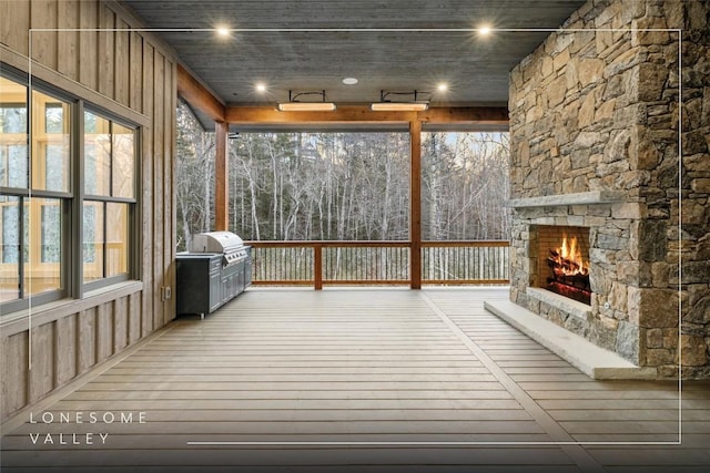 unfurnished sunroom featuring an outdoor stone fireplace and a healthy amount of sunlight