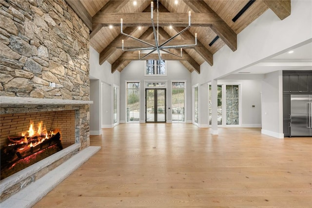 unfurnished living room with wood ceiling, light wood-style flooring, beamed ceiling, a stone fireplace, and high vaulted ceiling