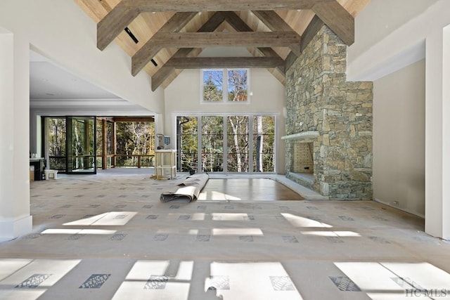 unfurnished living room with high vaulted ceiling, beam ceiling, plenty of natural light, and wooden ceiling