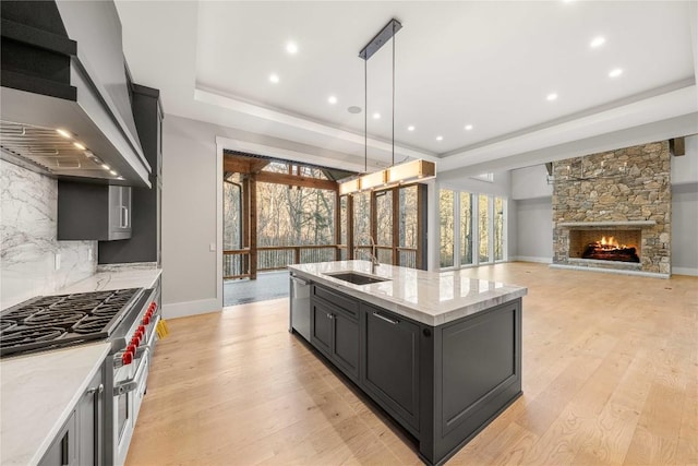 kitchen featuring a sink, a raised ceiling, dishwasher, wall chimney exhaust hood, and cooktop