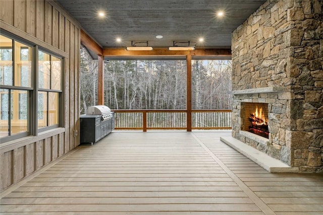 unfurnished sunroom featuring an outdoor stone fireplace