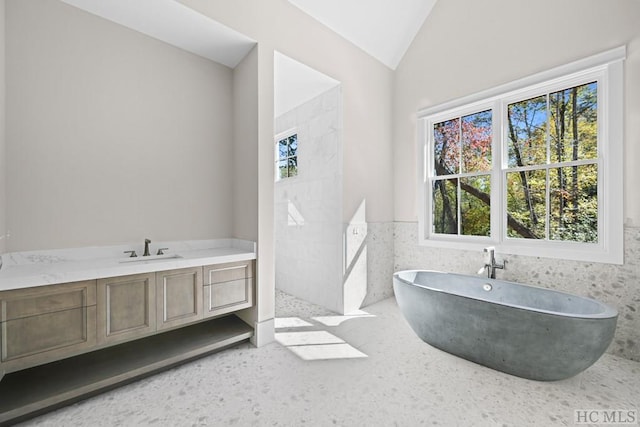 bathroom featuring vanity, vaulted ceiling, tile walls, and plus walk in shower