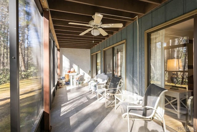 sunroom featuring ceiling fan, beam ceiling, and a wealth of natural light