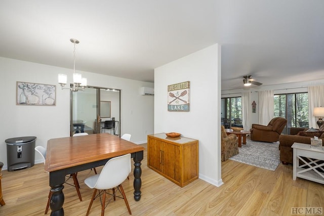 dining area featuring light hardwood / wood-style floors, ceiling fan with notable chandelier, and an AC wall unit