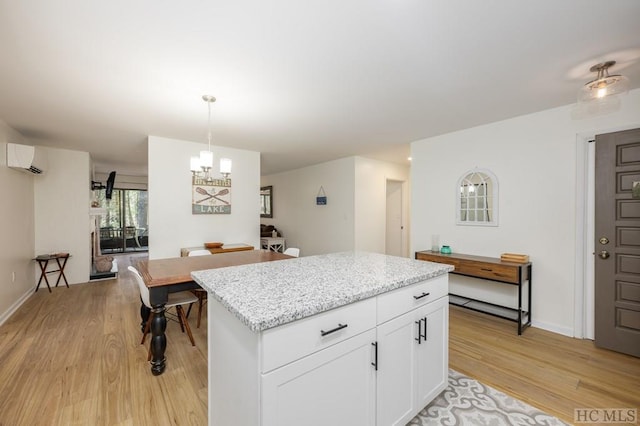 kitchen featuring hanging light fixtures, white cabinets, light hardwood / wood-style flooring, and a wall unit AC