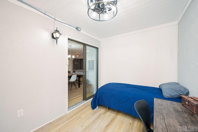 bedroom featuring an inviting chandelier, crown molding, and hardwood / wood-style floors