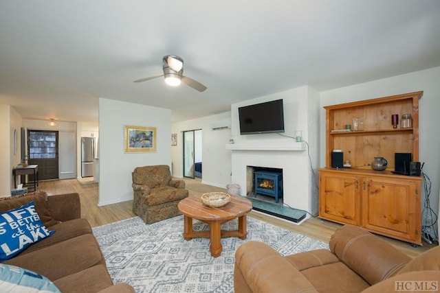 living room with ceiling fan, a wall mounted AC, and light wood-type flooring