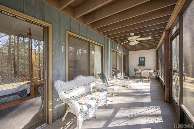 sunroom / solarium featuring ceiling fan and beamed ceiling