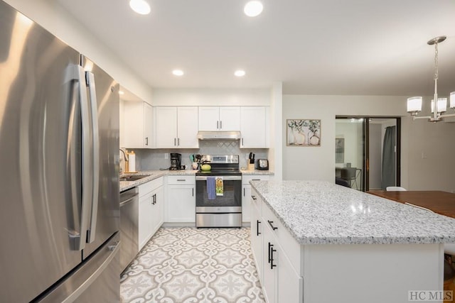 kitchen with white cabinets, a kitchen island, stainless steel appliances, backsplash, and hanging light fixtures